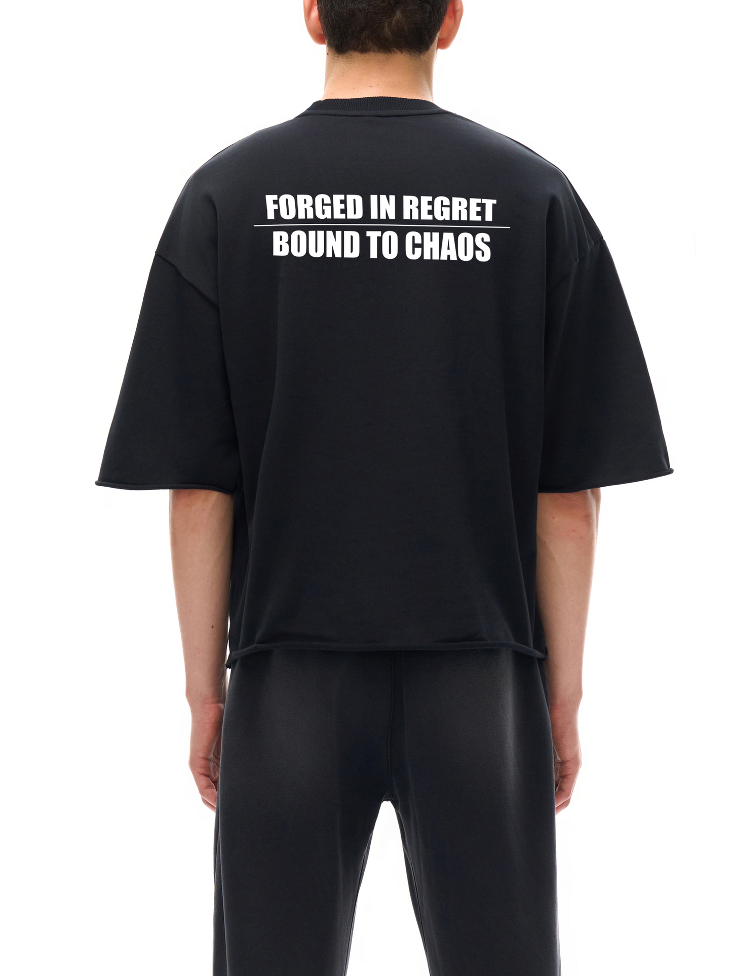 Model wearing black SXDGXDS t-shirt with "Forged in Regret / Bound to Chaos" text on the back