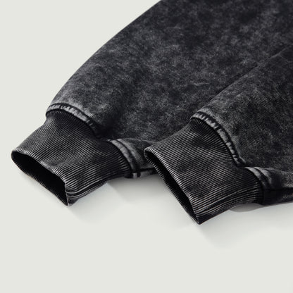 Detail shot of black snow-wash hoodie cuff showing thick cotton fabric and ribbed finish.