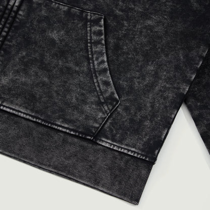 Detail shot of black snow-wash hoodie hem showing washed fade pattern and stitching.