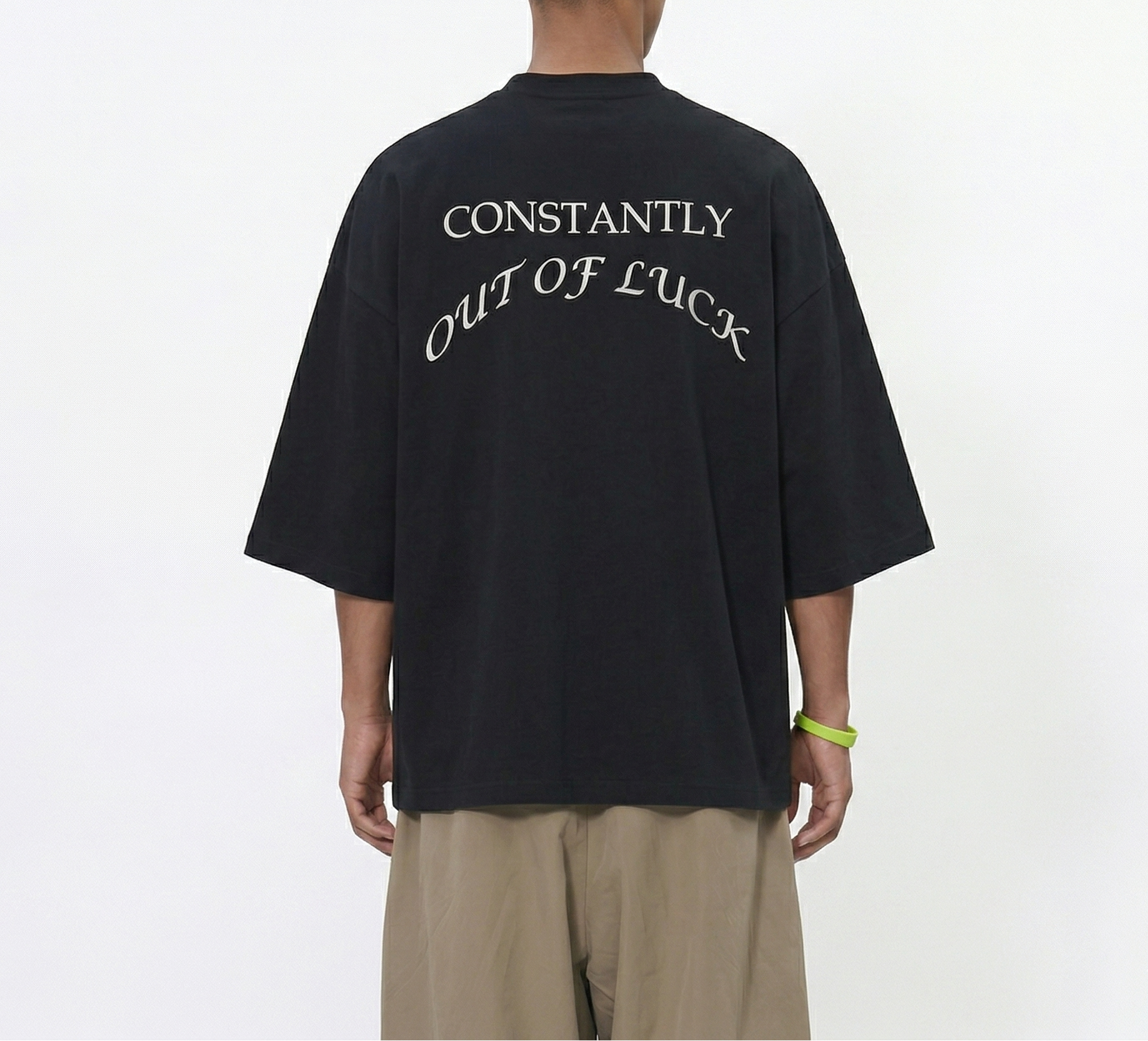 Person wearing a black t-shirt with text on the back, standing against a white background
