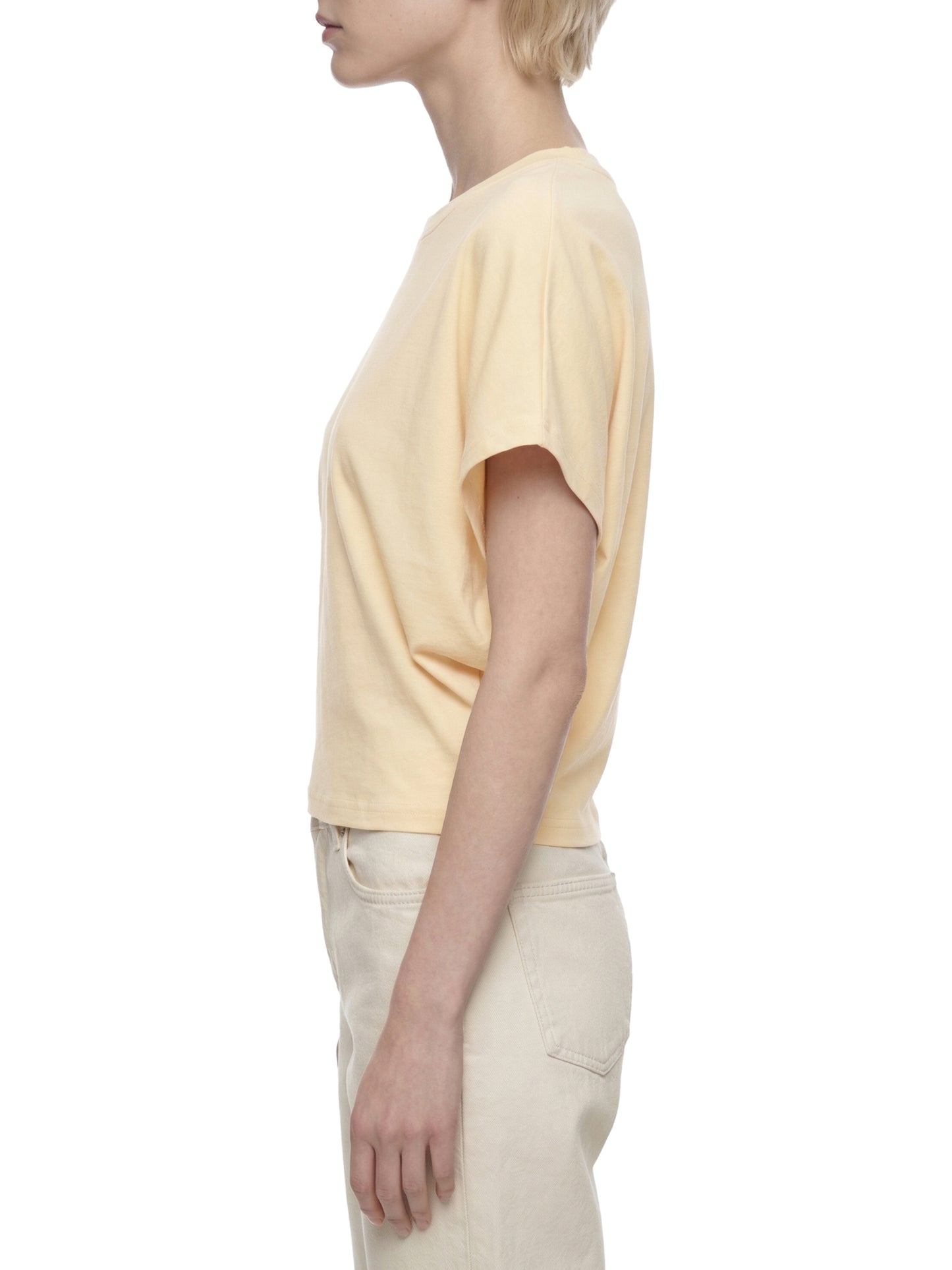 Person wearing a light yellow t-shirt and beige pants on a white background
