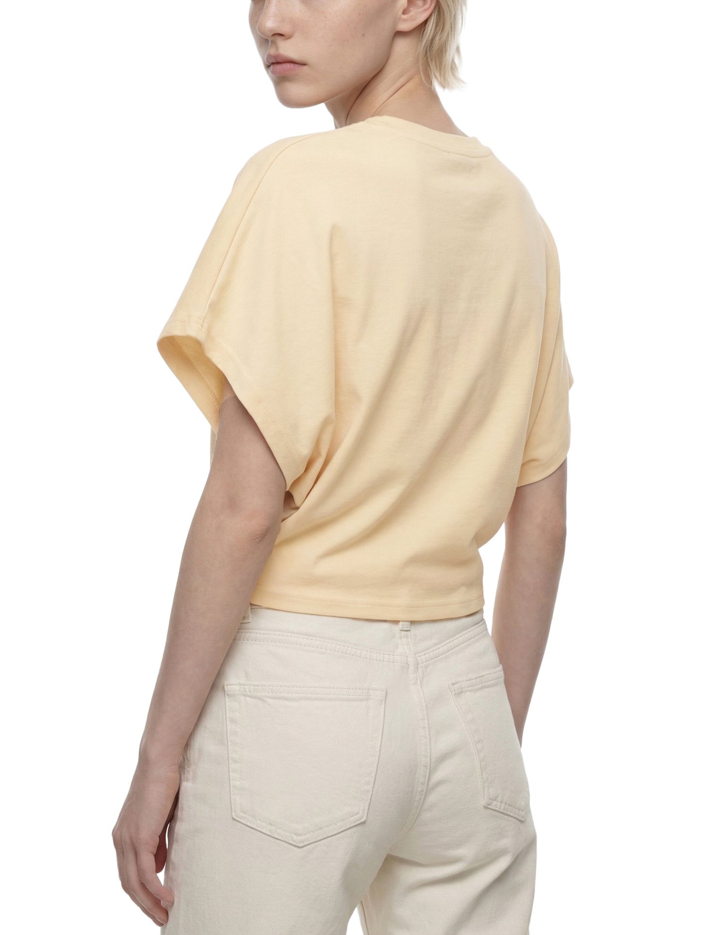Person wearing a light yellow top and beige pants on a white background