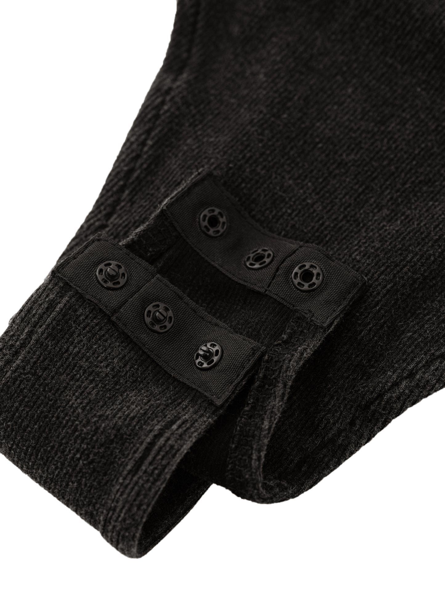 Close-up of black body suit with button on a white background