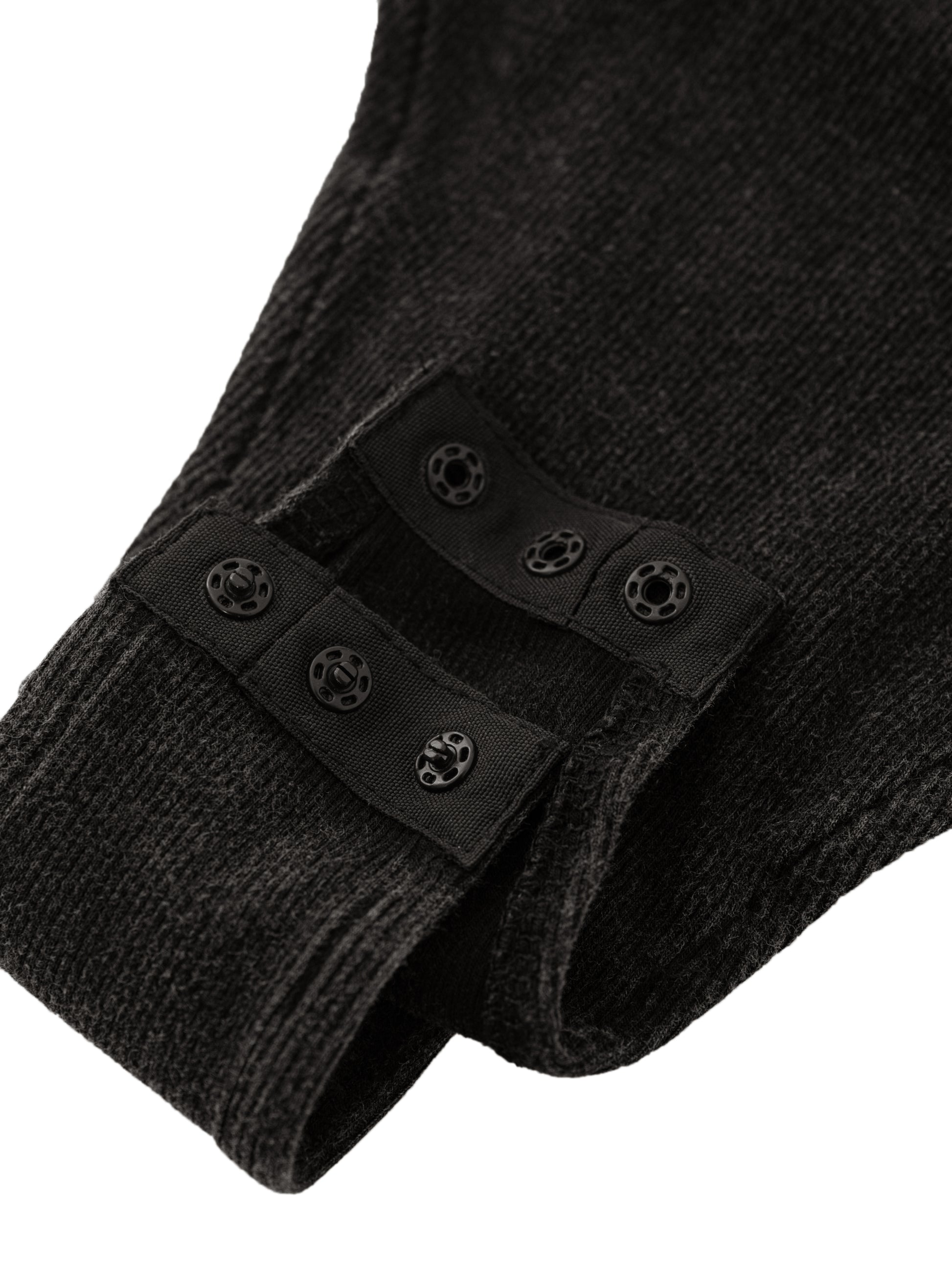 Close-up of black body suit with button on a white background