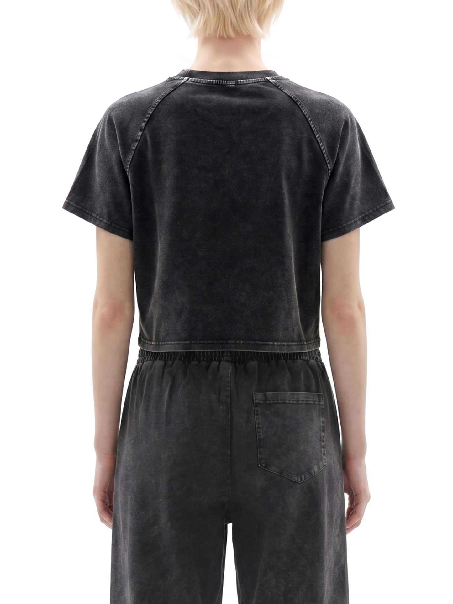 Person wearing a black distressed jumpsuit on a white background