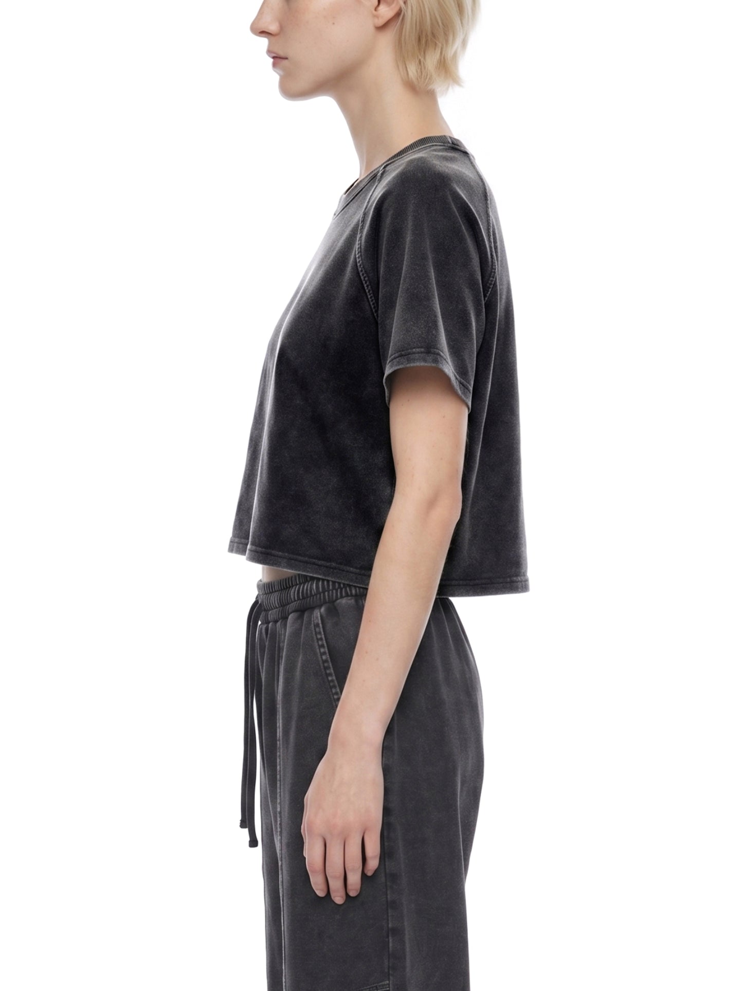 Person wearing a black distressed t-shirt and pants on a white background