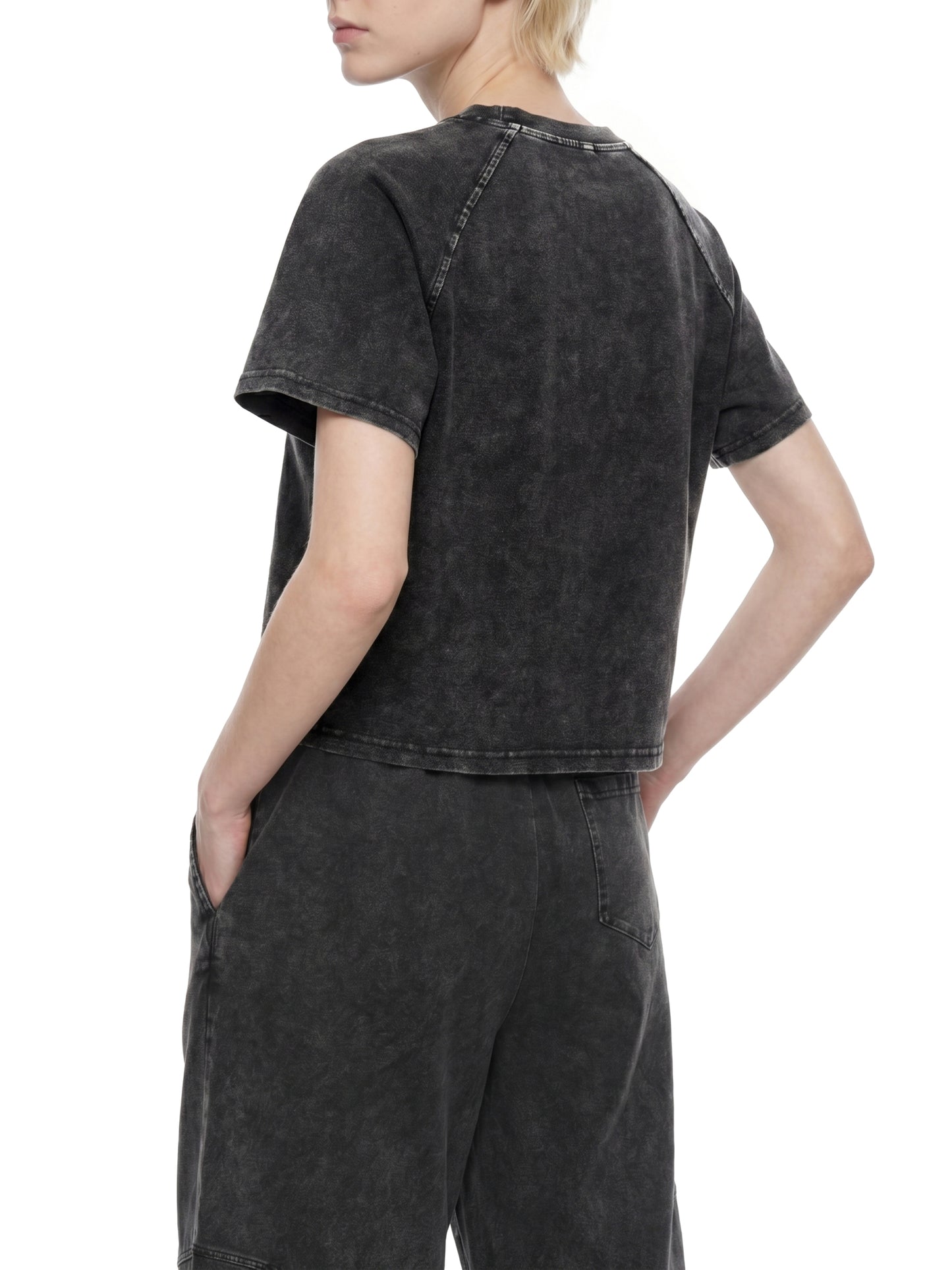 Person wearing a black acid-wash t-shirt and pants on a white background